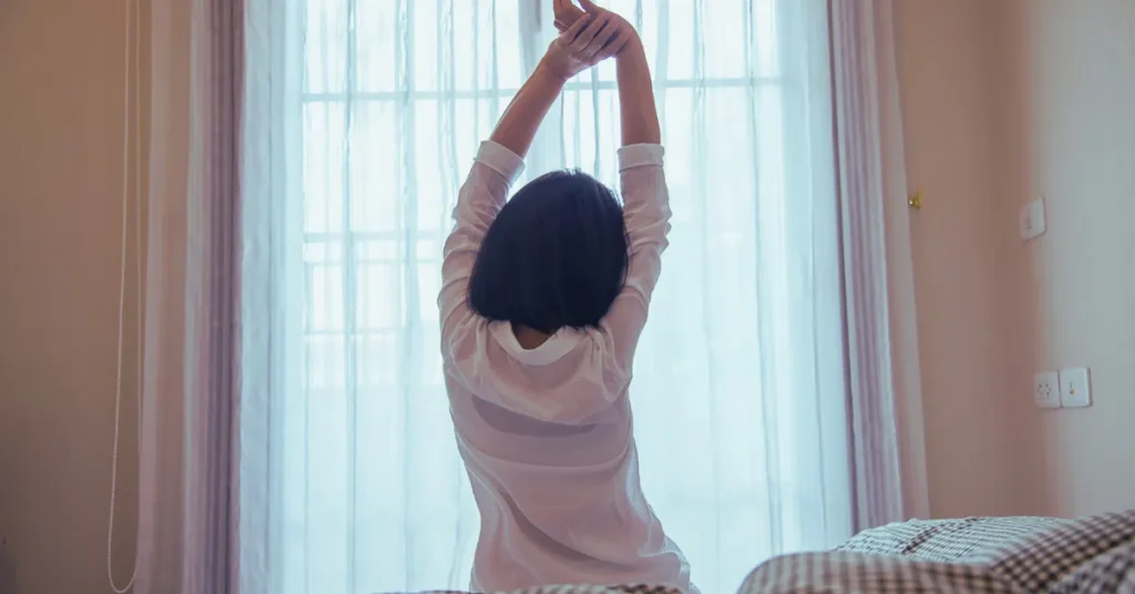 Morning Routine for Success - Start Your Day Like the Top 1% Morning Routine for Success - A woman stretching in front of a window, signifying the importance of starting the day with energizing habits for success.