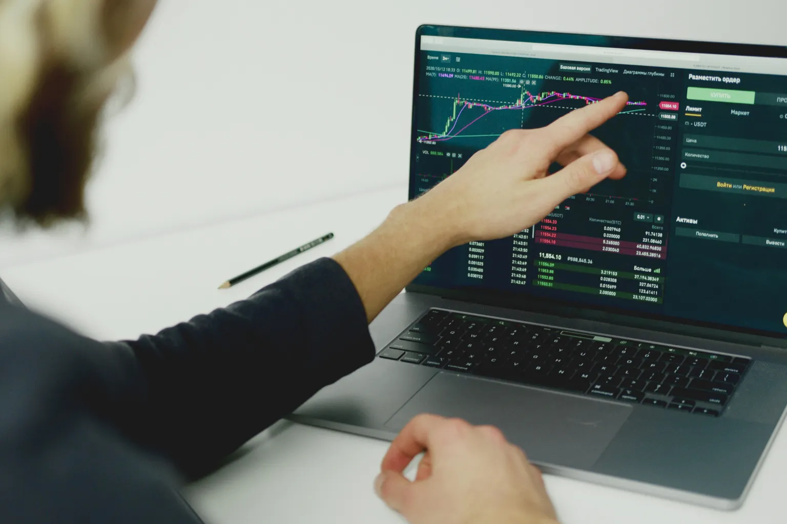 Person pointing at laptop with stock charts illustrating AI-driven trading and algorithmic markets
