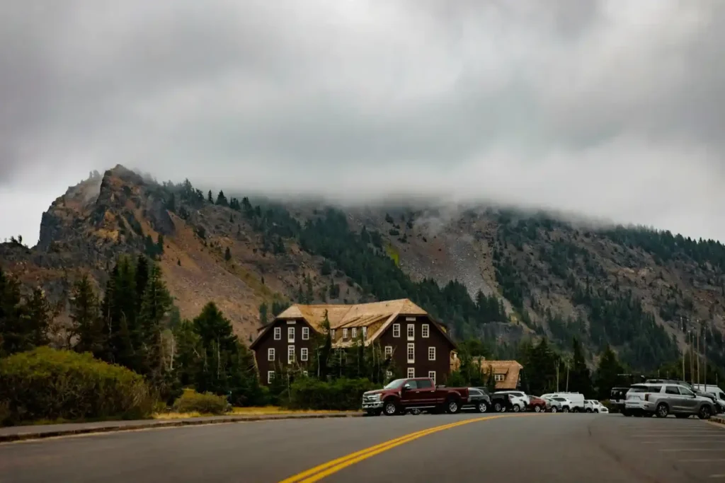 Mountain lodge at a US national park Lodges Now Cost Triple with cloudy sky and parked cars, symbolizing sharp rise in park stay costs shocking tourists