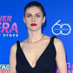 Alexandra Daddario posing at TAG Heuer Carrera 60 Years of Carrera event in black dress with bold red lipstick