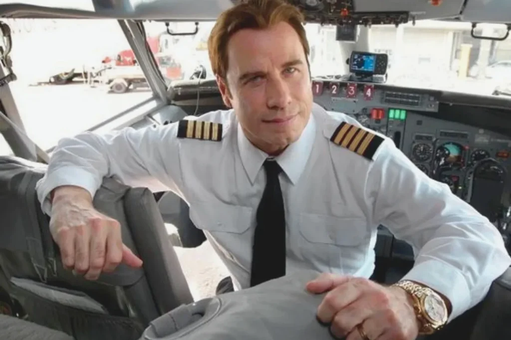 John Travolta in Cockpit After Earning Jet Pilot Rating John Travolta in a pilot uniform inside an aircraft cockpit highlighting his aviation career