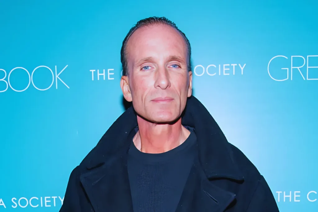 Home | RIGHWAY 11 Portrait of Peter Greene at a public event against a blue backdrop.