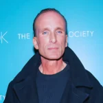 Portrait of Peter Greene at a public event against a blue backdrop.