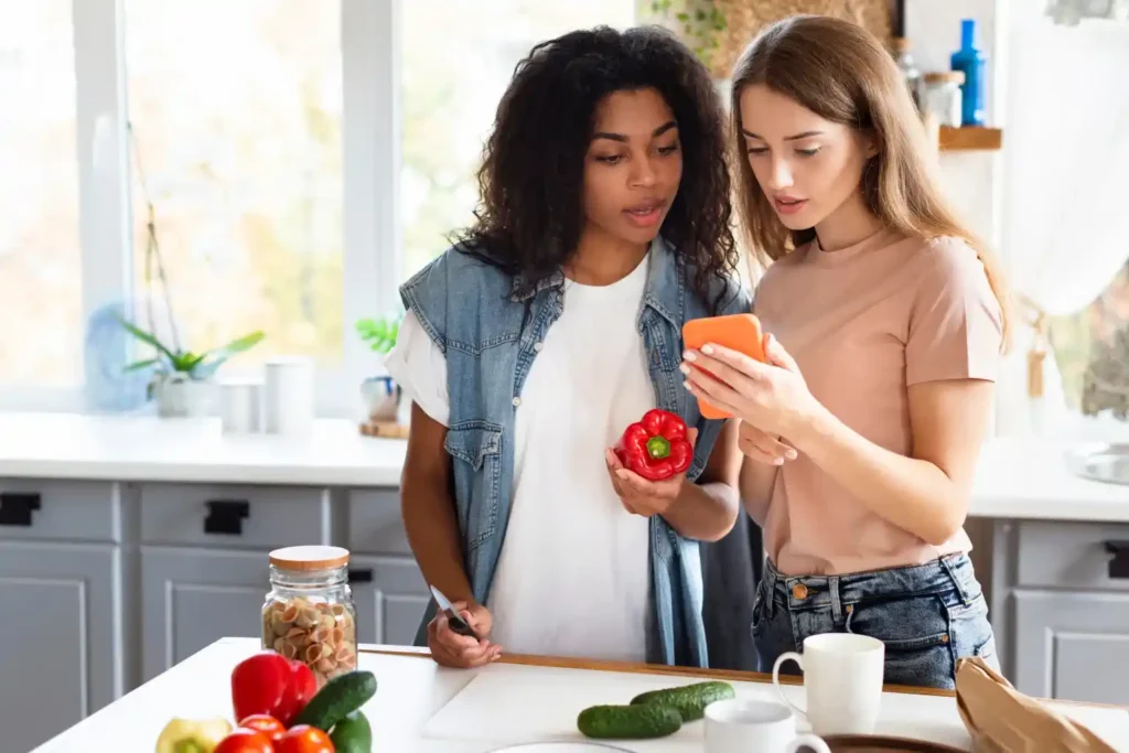 Apply for SNAP Benefits Online – Food Assistance Made Easy Two women checking phone while shopping groceries, learning how to apply for SNAP benefits online
