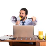 Man using megaphone at laptop illustrating strategies to get promoted at work and boost career growth