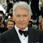 Harrison Ford net worth spotlight at red carpet event in classic black tuxedo