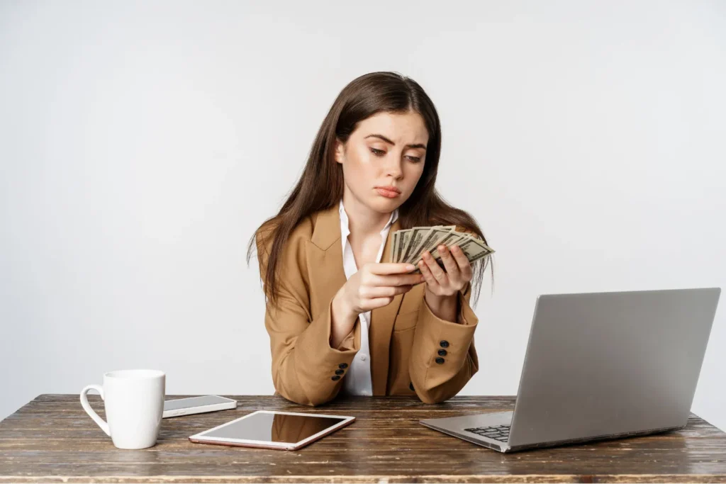 Woman counting cash while budgeting on laptop, how to save money fast on a low income