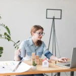 How to Start a Side Hustle - Woman working on laptop planning a safe side hustle business from home in 2026 with financial strategy tools