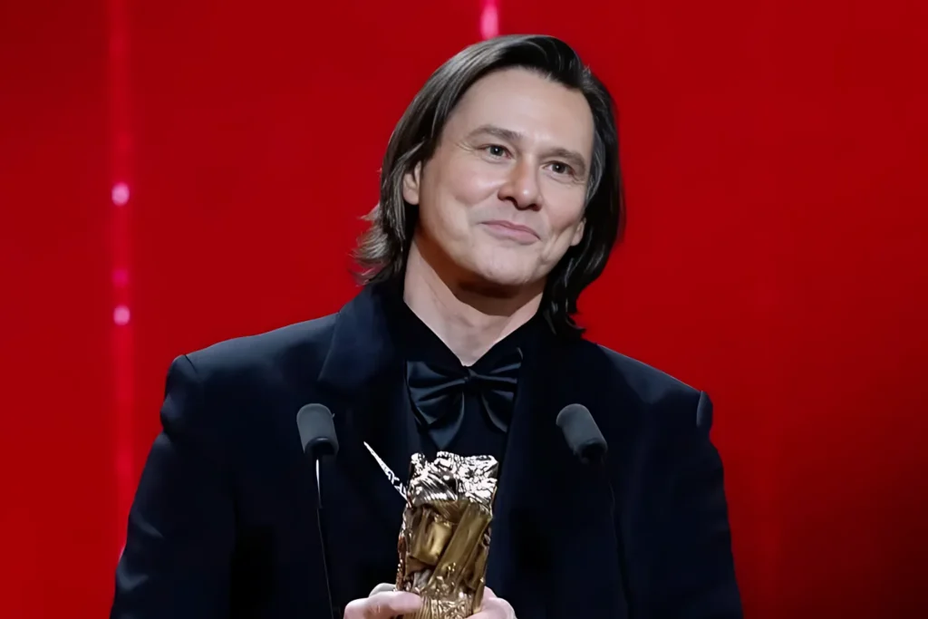Jim Carrey holding award during ceremony, highlighting his net worth and Hollywood career success