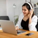 Woman working on laptop with headphones learning how to find remote jobs from home online